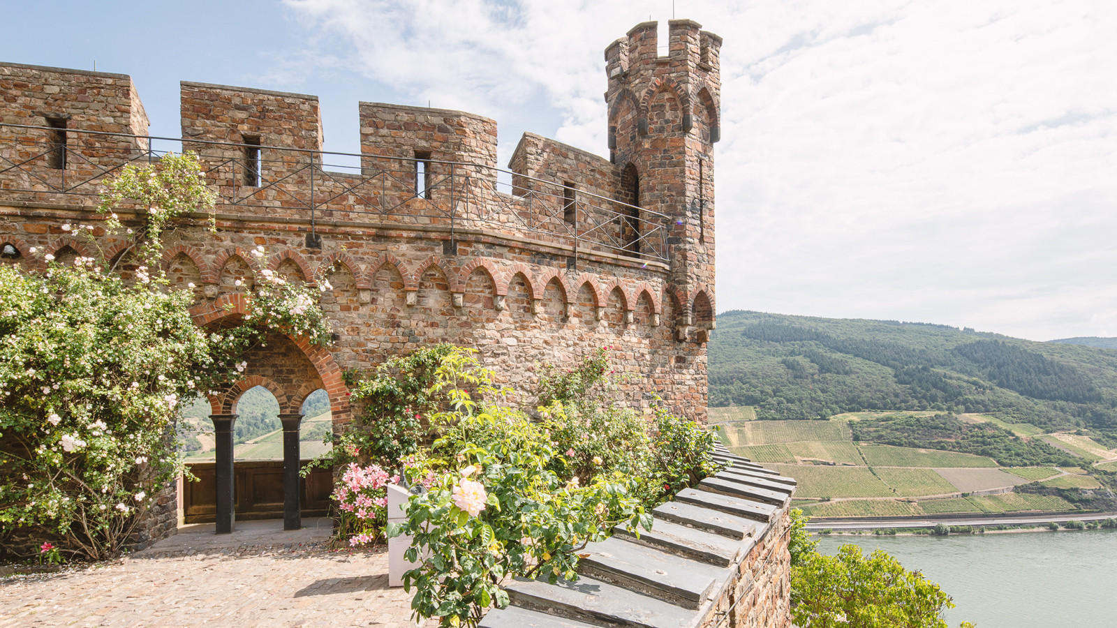 Außenbereich mit Rosen und Blick auf den Rhein von der Burg Sooneck
